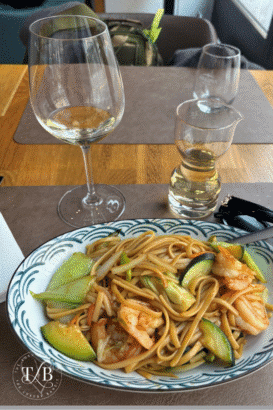Elegant shrimp noodle meal paired with wine, enjoyed abroad while budgeting travel expenses through a high yield savings account. Luxury travelers benefit from yield savings high and high interest savings account USA returns.
