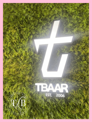 Bright neon TBAAR logo glowing against a lush green moss wall at the Duluth GA location. This trendy boba tea Atlanta spot offers an affordable boba experience with stylish, photo-worthy interiors that elevate your visit.